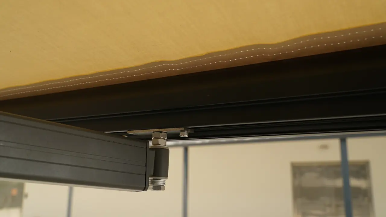 Awning detail showing fabric stitching, a frame rail and the arm connection. Each material and moving interface needs suitable care.
