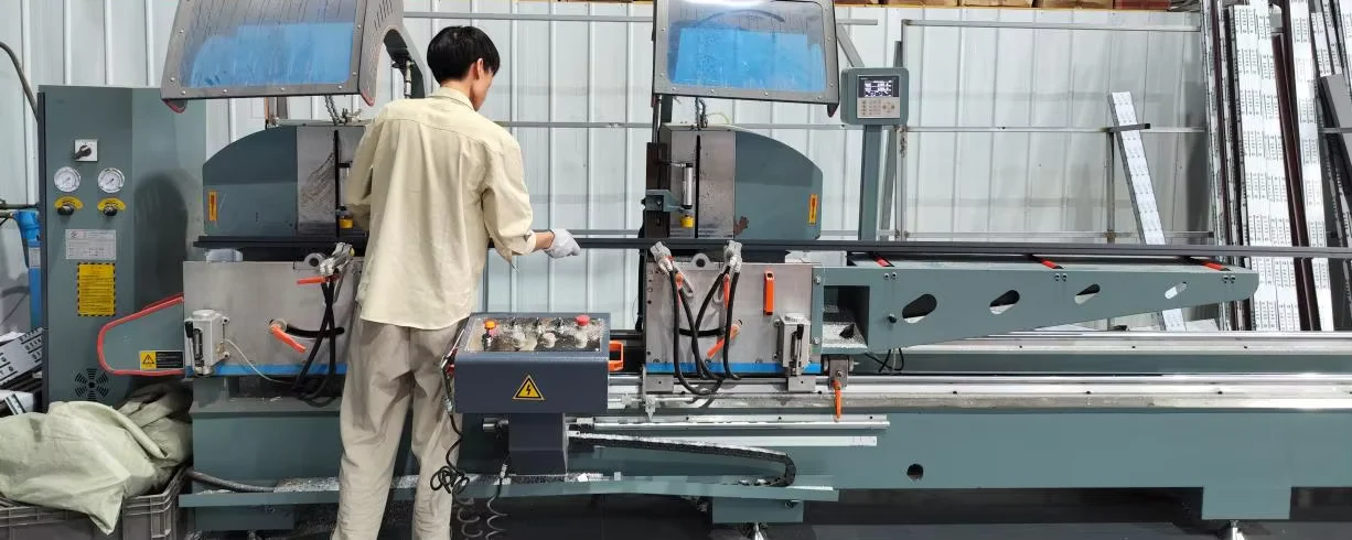 An operator positions a profile at a two-head cutting station.